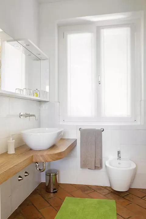 Il bagno del monolocale con la doccia e le piastrelle chiare